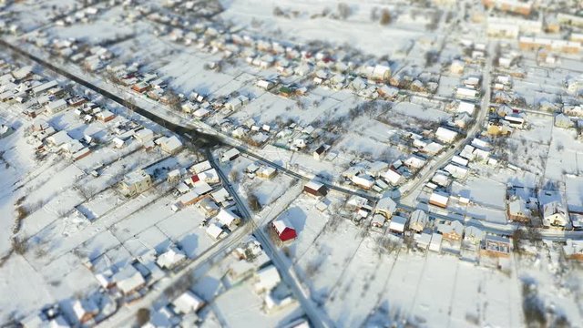 Aerial survay over snowy crossroad in the village. Tilt shift miniature