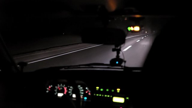 Car rides on the night road. Inside view. Dashboard, radio, DVR. Overtaking. Oncoming cars blind eyes. Headlights light the way. Road signs and markings. Traffic Laws. Track out of town