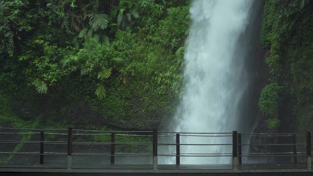 Beautiful landscape of Sawer Waterfall and female visitor walking on the bridge in Sukabumi, West Java, Indonesia. Shot in 4k resolution