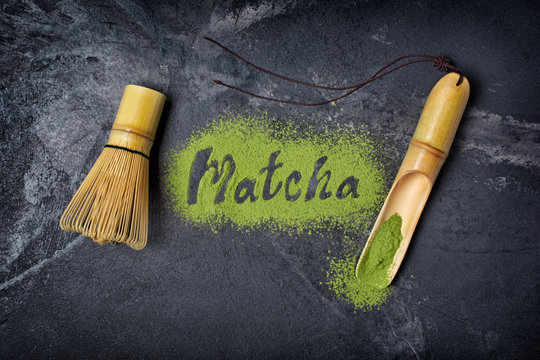 Fototapeta Lettering from green matcha tea with bamboo scoop and whisk on black background