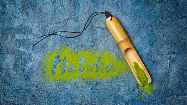 Fototapeta Lettering from green matcha tea with bamboo scoop on blue concrete background