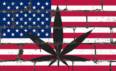 Graffiti street art spray drawing on stencil. Cannabis leaf on brick wall with flag USA