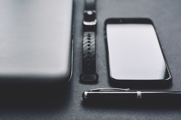 mobile phone with notebook and pen on black background