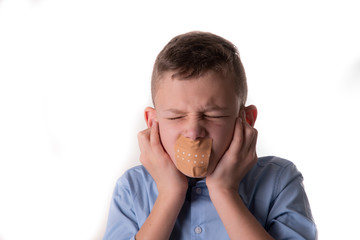 Child speechless with a plaster over his mouth also holds his ears to white background