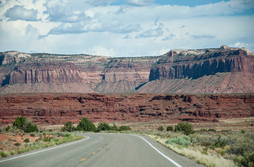 Road in desert with a turn directly in front of red hills