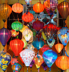 Fototapeta na wymiar Colourful fabric lanterns hang outside a shop in a street in the historic UNESCO listed Vietnamese town of Hoi An.