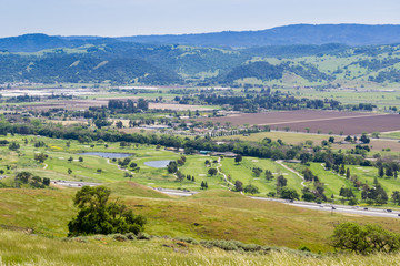 Fototapeta premium Aerial view of golf course and agricultural fields, mountain background, south San Francisco bay, San Jose, California