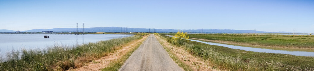 Fototapeta na wymiar Panoramic view of levee going through the marsh and ponds in south San Francisco bay, California
