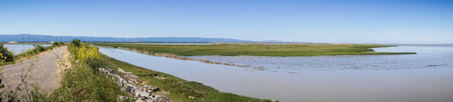 Panoramic view of levee going through the marsh and ponds in south San Francisco bay, California