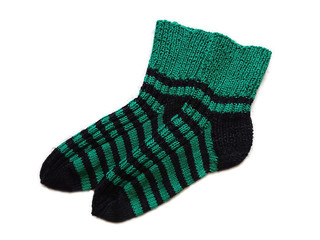A pair of hand knitted handmade natural wool striped pattern black and green warm socks accessory isolated on the white background 