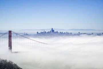 Golden Gate and the San Francisco bay covered by fog, the financial district skyline in the background, as seen from the Marin Headlands State Park, California