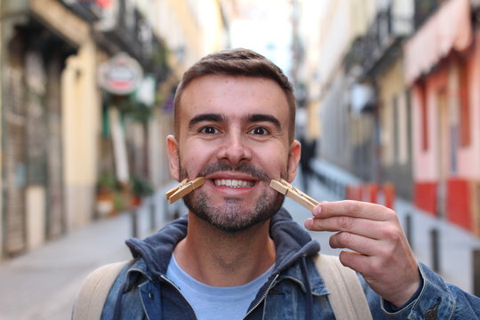 Young male faking a smile with clothespins