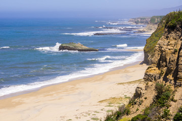 Fototapeta na wymiar Cliffs and sandy beach on the Pacific Ocean coastline near Half Moon Bay, California