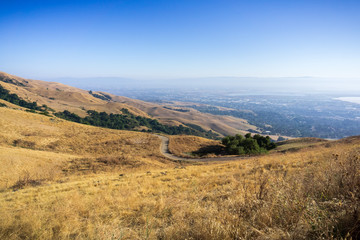 Fototapeta na wymiar Trail through the golden hills of Mission Peak preserve; downtown San Jose in the background, south San Francisco bay, California