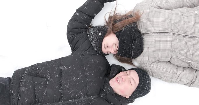 Lovely couple lying on snow and smile to each other. 4K Footage - Video
