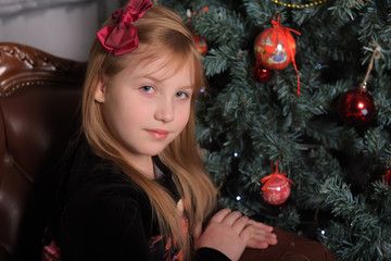 girl blonde child in black with red dress in christmas by the christmas tree