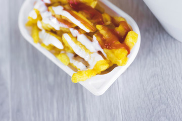 French fries served in a white non ecological plastic box to take away, served with tartare sauce and tomato ketchup