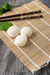 Japanese mochi with mint leaves on the wooden mat. Japan traditional rice cake.