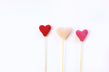 Three knitted hearts on a sticks.