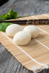 Japanese mochi with mint leaves on the wooden mat. Japan traditional rice cake.