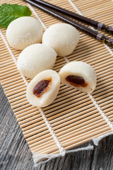 Japanese mochi with mint leaves on the wooden mat. Japan traditional rice cake.