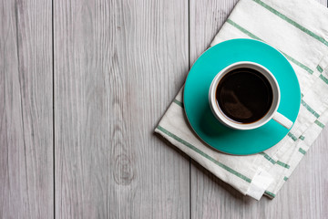 green turquoise cup of hot coffee with wooden background .top view