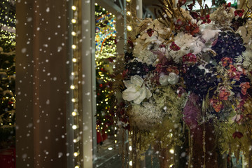 Bouquet of flowers on the street at night it snows. Holiday decoration of the city. Place for your text.