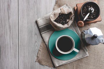 black coffee in a coffee cup with coffee beans and coffee grinder on wooden table.  top view