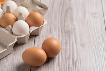 Raw eggs in egg box on wooden background.