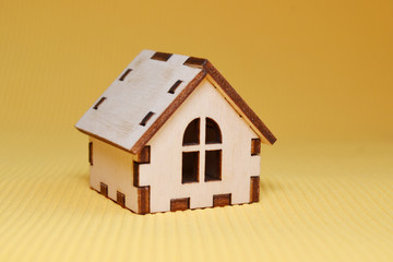 Wooden toy house model on yellow background side view