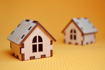 Two wooden toy house model on yellow background