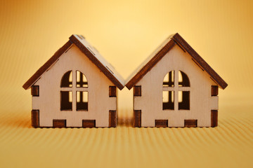 Two wooden toy house model on yellow background front view