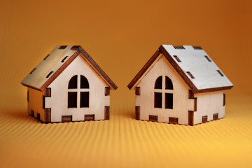 Two wooden toy house model on yellow background side view
