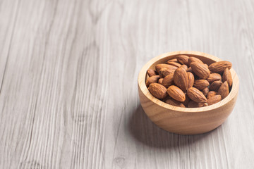 Almonds in a wooden bowl with wooden background 