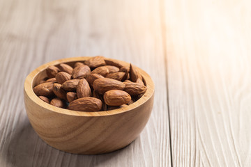 Almonds in a wooden bowl with wooden background .top view .