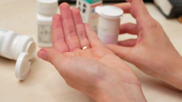 Woman pouring bunch of prescription yellow opiate pills into hand