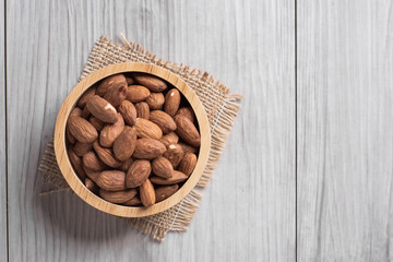 Almonds in a wooden bowl with wooden background .top view .