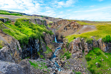 Fototapeta na wymiar Rocky landscape with water course coming down from Hengifoss and Litlanesfoss waterfalls