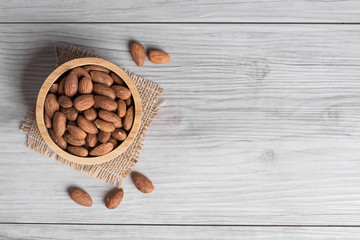 Almonds in a wooden bowl with wooden background .top view .