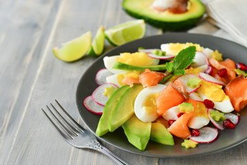 Salad with organic avocado and with salmon, eggs and radish. Decorated with mint leaf and pomegranate. Healthy lunch, vegetarian food, diet dish. food for weight loss. Selective focus and copy space