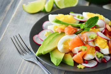 Salad with organic avocado and with salmon, eggs and radish. Decorated with mint leaf and pomegranate. Healthy lunch, vegetarian food, diet dish. food for weight loss. Selective focus and copy space