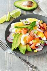 Salad with organic avocado and with salmon, eggs and radish. Decorated with mint leaf and pomegranate. Healthy lunch, vegetarian food, diet dish. food for weight loss. Selective focus and copy space