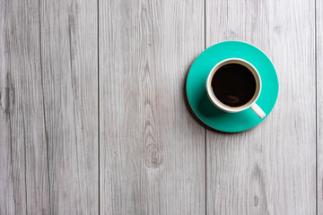 green turquoise cup of hot coffee with wooden background .top view