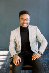 Obraz premium Smiling cheerful isolated portrait of african american business man in stylish suit and glasses on a dark background