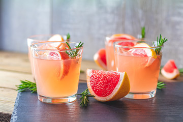 Fresh pink alcoholic cocktail with grapefruit, ice and rosemary