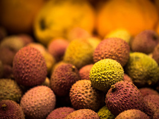 Plenty of lychee fruits at a market with oranges in the background