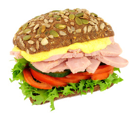 Ham salad sandwich in a pumpkin and sunflower seed dark rye bread roll isolated on a white background