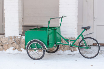 Fototapeta na wymiar Amsterdam, The Netherlands. Winter, Green trolley on a bicycle stands on white snow.