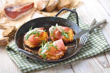 Deftige Kartoffelrösti mit Südtiroler Speck, Parmesan und Rucola in der Eisenpfanne rustikal serviert – Potato rosti with South Tyrolean bacon, parmesan cheese and rocket salad served in a frying pan