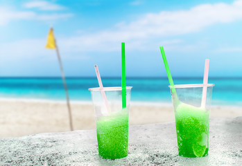 Two apple green drift-ice with straw on the beach. In the background is blue sky, palms, sea nd sandy beach. This is situated in tropical resort in Asia © Jana